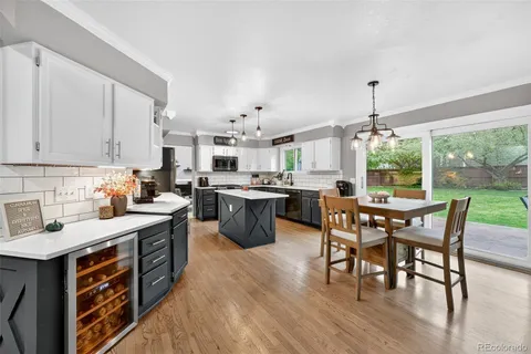a open dining room with stainless steel appliances granite countertop a kitchen island a stove a table and chairs