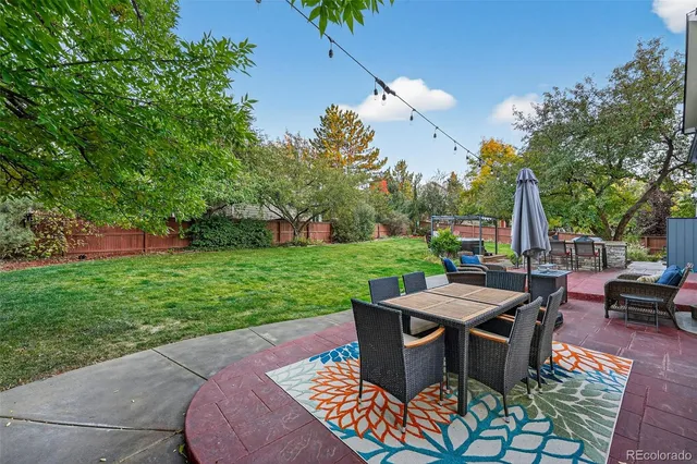 a view of a patio with table and chairs potted plants and a large tree