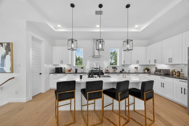 a kitchen with stainless steel appliances kitchen island granite countertop a dining table chairs and white cabinets