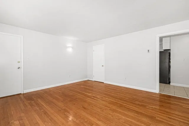 a view of empty room with wooden floor