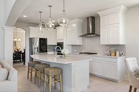 a kitchen with stainless steel appliances granite countertop a stove a sink a refrigerator a center island a dining table and chairs