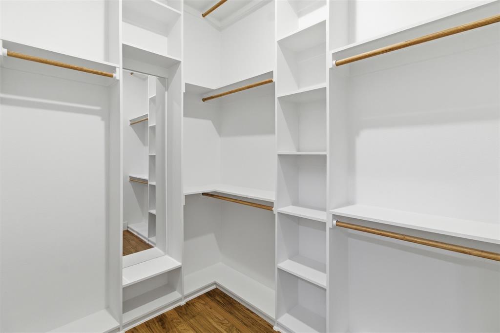 429 Waterboard Road Trinidad, TX 75163 - Photo 15 of 25 Walk-in closet featuring built-in white shelving, multiple hanging rods, corner shelving units, a full-length mirror, and wood-finish flooring