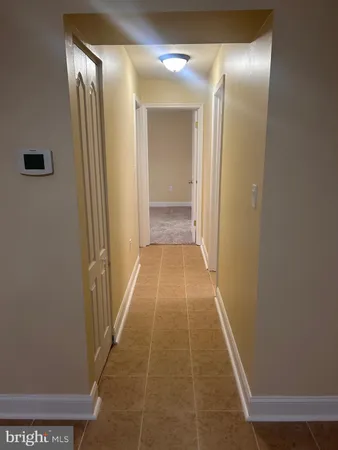 a view of a refrigerator in kitchen and an empty room