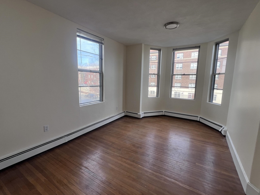 394 Broadway, Unit 3 Somerville, MA 02145 - Photo 7 of 12 an empty room with wooden floor and windows