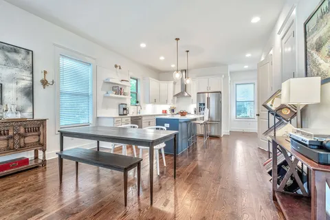 a kitchen with stainless steel appliances a dining table chairs stove and cabinets