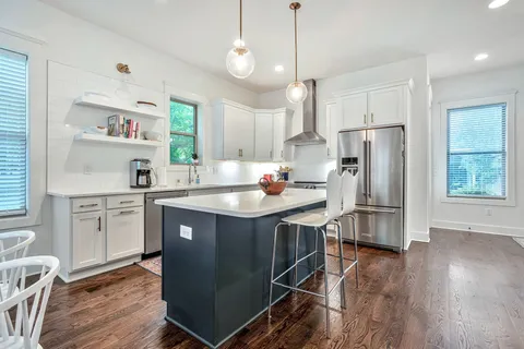 a kitchen with kitchen island granite countertop a sink a counter space appliances and cabinets