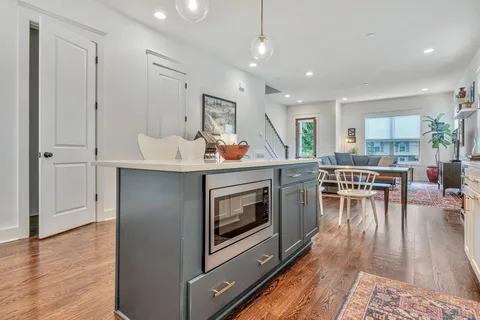 a kitchen with a stove a refrigerator and a dining table with wooden floor