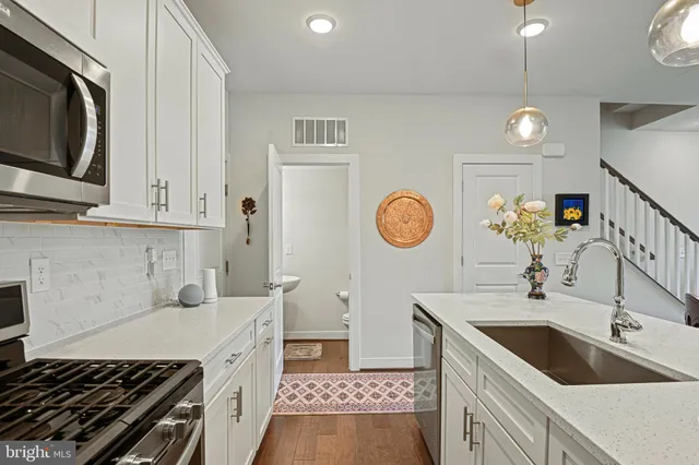 a kitchen with a sink and a stove top oven with wooden floor
