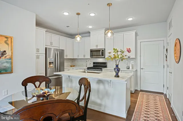 a kitchen with refrigerator a stove a sink cabinets a dining table and chairs