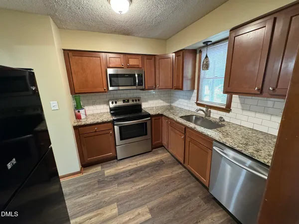 a kitchen with stainless steel appliances granite countertop a stove refrigerator sink and microwave