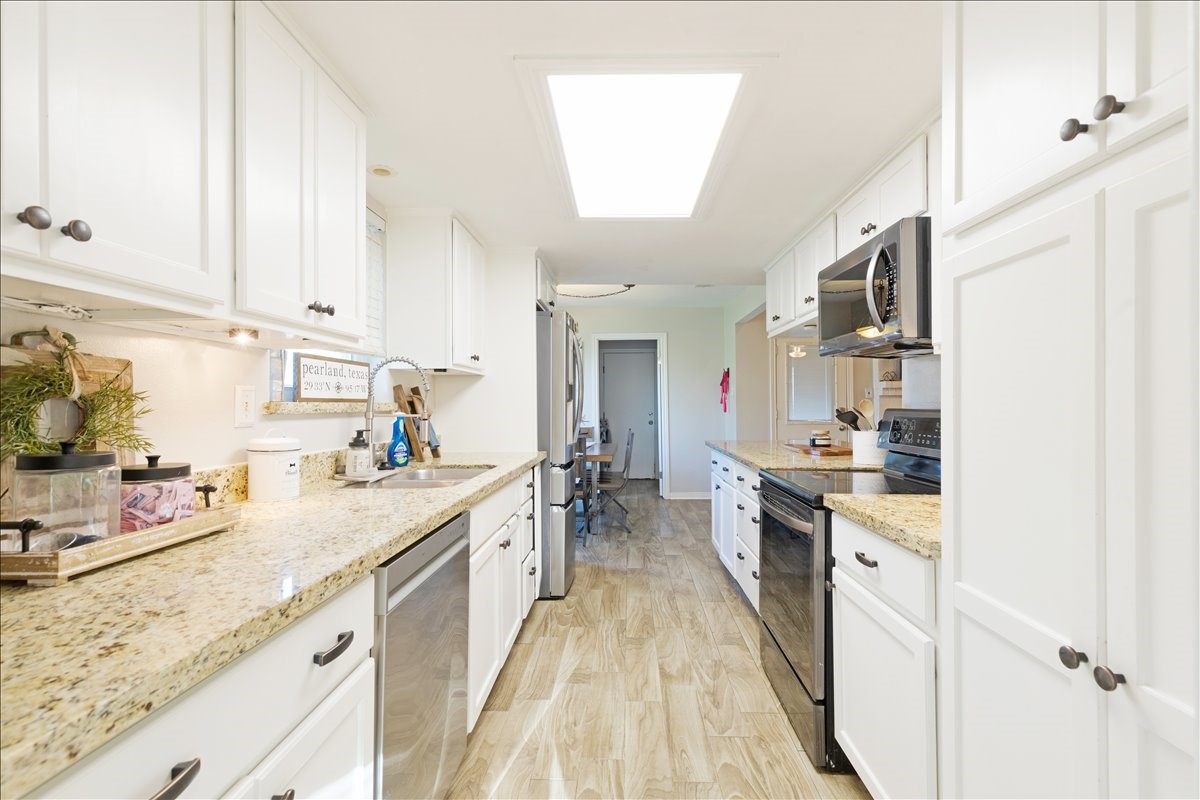 3809 Wingtail Way Pearland, TX 77584 - Photo 11 of 29 a kitchen with granite countertop a sink stove refrigerator and cabinets