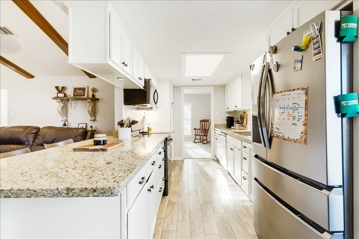 3809 Wingtail Way Pearland, TX 77584 - Photo 10 of 29 a large kitchen with kitchen island granite countertop a refrigerator a stove a sink and a dining table with wooden floor