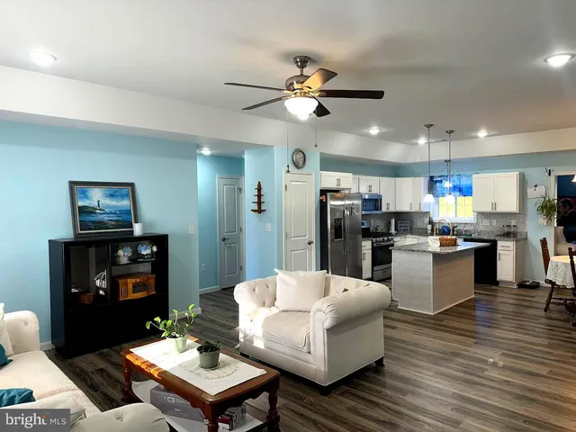 a living room with stainless steel appliances kitchen island a table and chairs