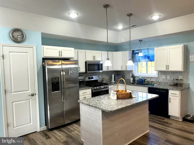 a kitchen with stainless steel appliances granite countertop a refrigerator a stove a sink and a microwave