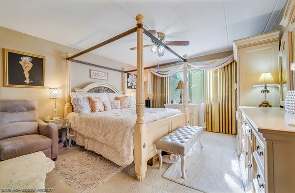 a bedroom with a bed a chandelier and flat screen tv