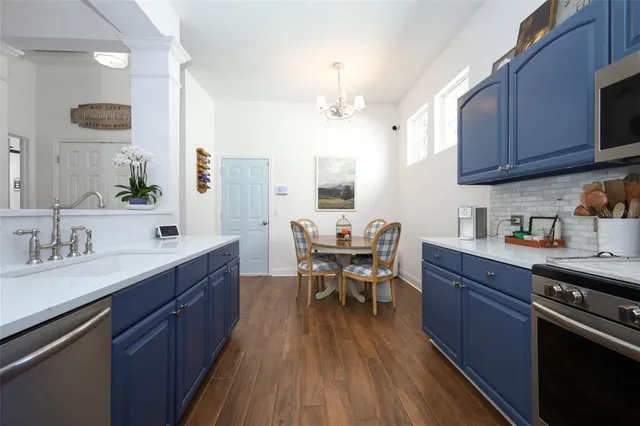 a kitchen with stainless steel appliances granite countertop wooden floors stove top oven with a dining table and chairs