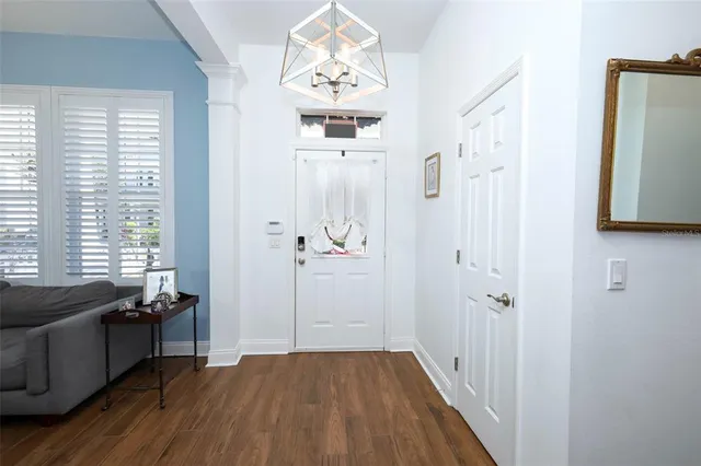 a view of a hallway to a livingroom with wooden floor and a window