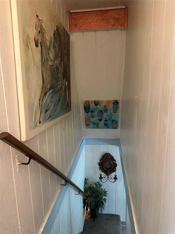 355 Spring Valley Street Gun Barrel City, TX 75156 - Photo 24 of 27 Stairwell featuring vertical paneling, a wood handrail, and sconce lighting