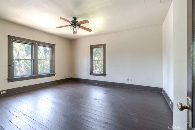 an empty room with wooden floor chandelier and windows