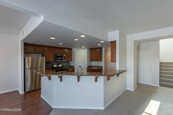 a view of kitchen with stainless steel appliances kitchen island refrigerator stove and wooden floor