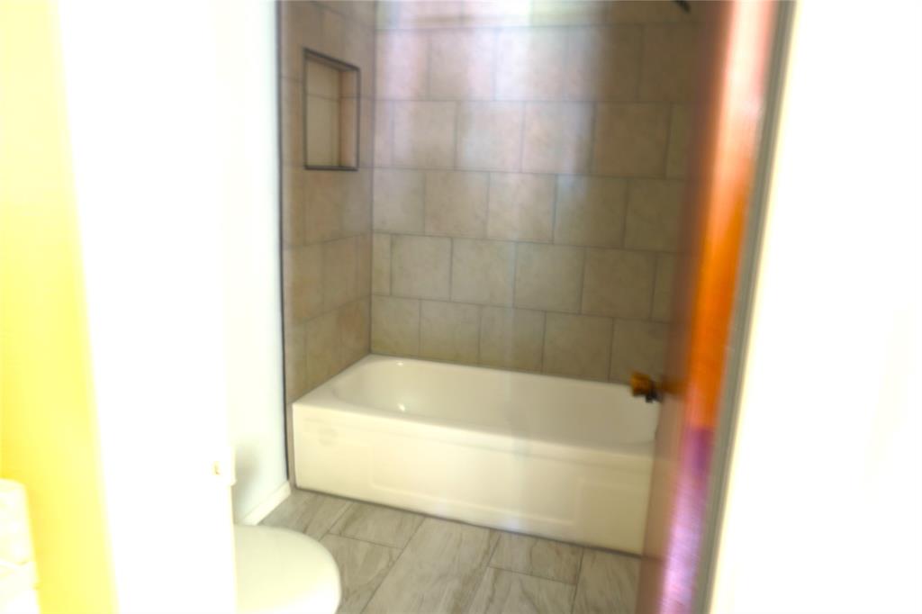 300 Coury Road Everman, TX 76140 - Photo 16 of 29 a bath tub sitting next to a white toilet