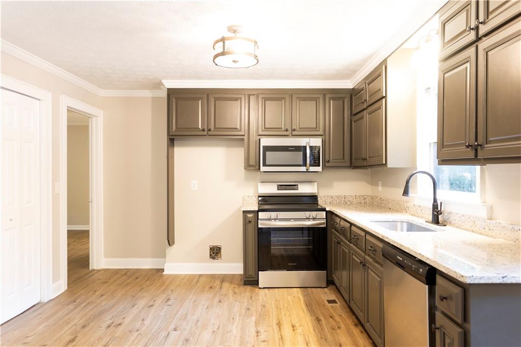 1149 Criswell Road Southeast Monroe, GA 30655 - Photo 11 of 60 a kitchen with stainless steel appliances granite countertop a sink stove and refrigerator