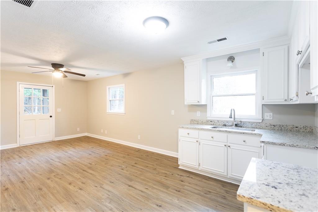 1149 Criswell Road Southeast Monroe, GA 30655 - Photo 18 of 60 a kitchen with granite countertop a sink cabinets wooden floor and a window