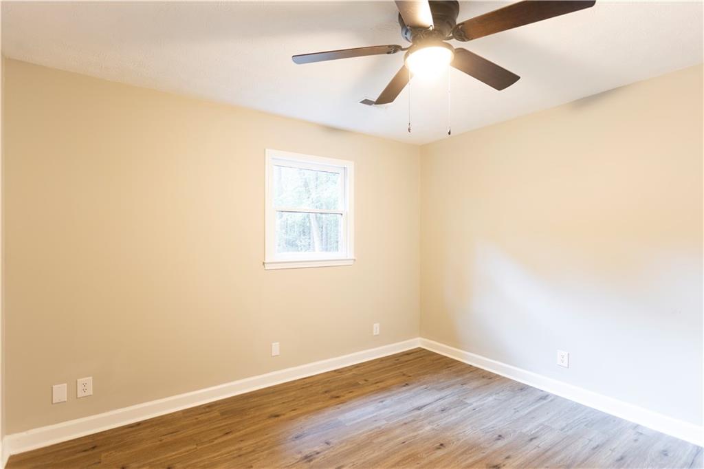 1149 Criswell Road Southeast Monroe, GA 30655 - Photo 26 of 60 an empty room with wooden floor chandelier fan and windows