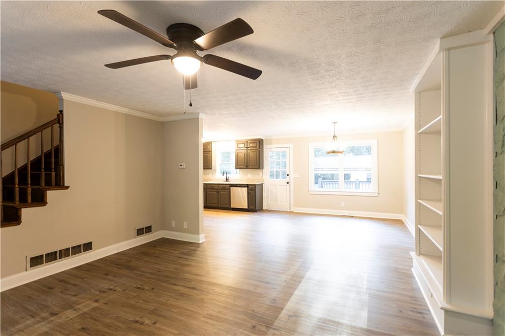 1149 Criswell Road Southeast Monroe, GA 30655 - Photo 8 of 60 a view of a big room with wooden floor a ceiling fan and windows