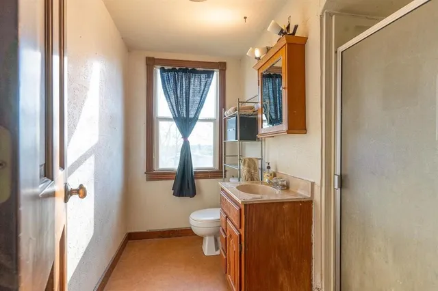 a bathroom with a granite countertop sink toilet and mirror