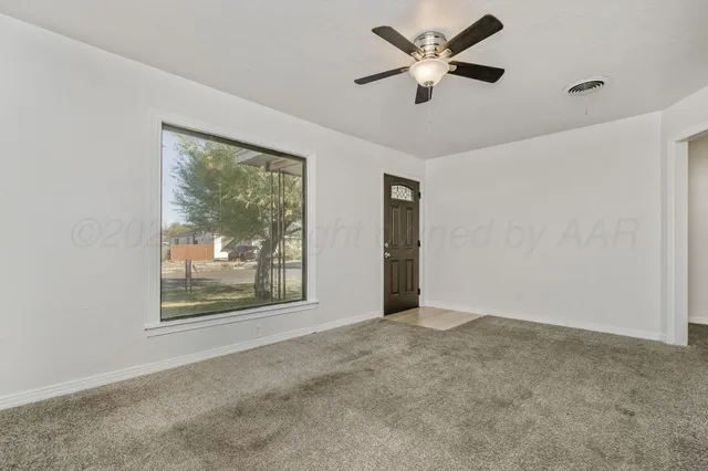 a view of an empty room with a window and a ceiling fan