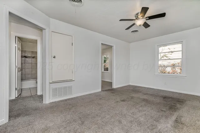 an empty room with fan and windows