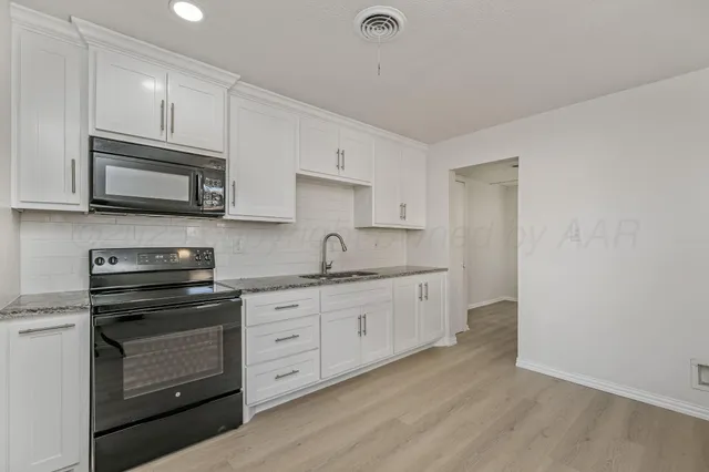 a kitchen with granite countertop white cabinets stainless steel appliances and a sink