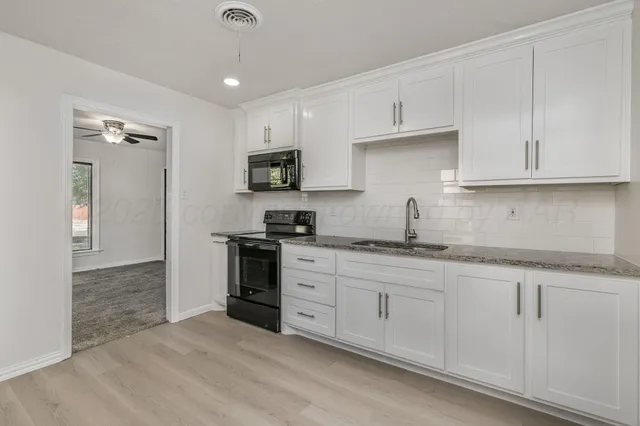 a kitchen with granite countertop a sink stainless steel appliances and cabinets
