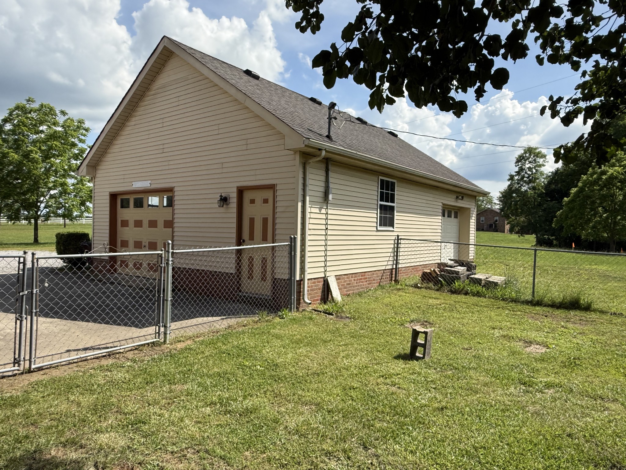 3168 Maxey Road Cedar Hill, TN 37032 - Photo 9 of 40 a backyard of a white house with potted plants and large tree