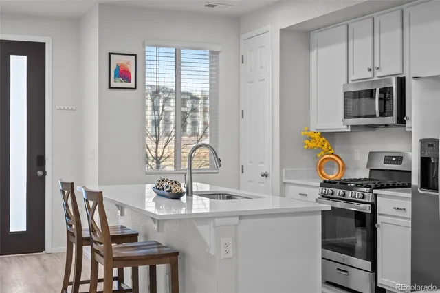 a kitchen with stainless steel appliances granite countertop a stove top oven a sink a dining table and chairs