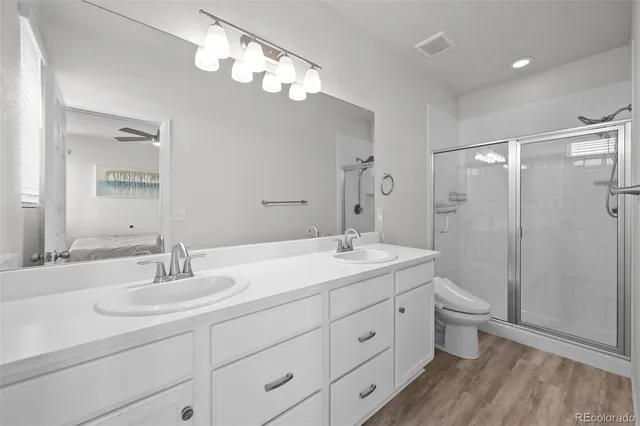 a bathroom with a double vanity sink toilet mirror and shower