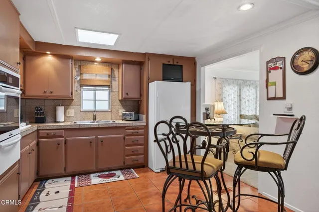 a kitchen with stainless steel appliances granite countertop a table and chairs in it