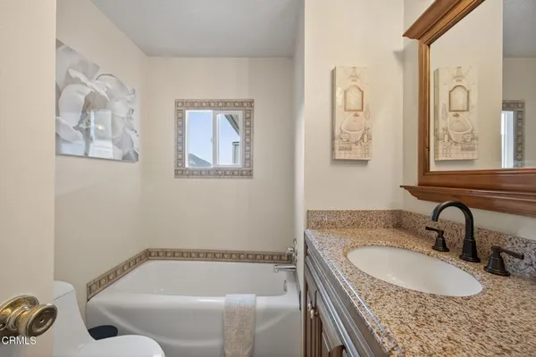 a bathroom with a granite countertop tub sink and mirror