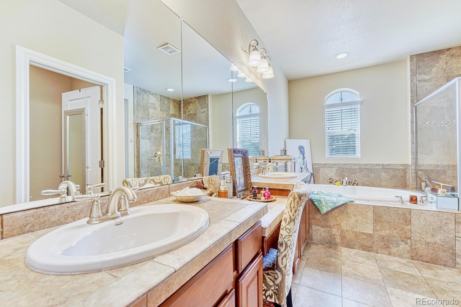 10120 RidgeGate Circle Lone Tree, CO 80124 - Photo 17 of 25 a bathroom with a double vanity sink a mirror and a bathtub