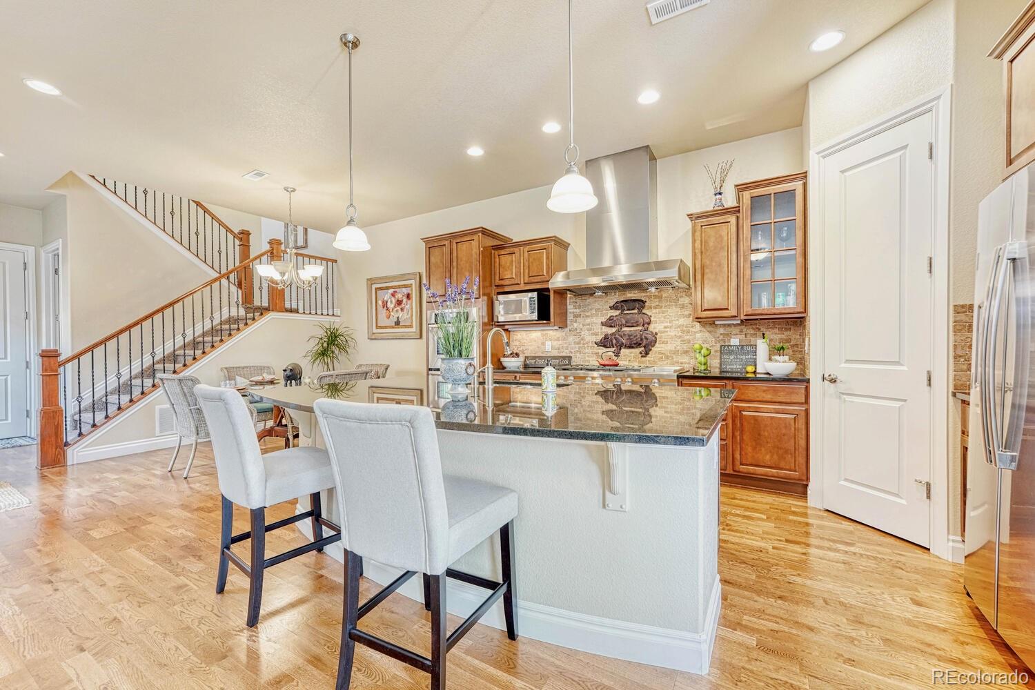 10120 RidgeGate Circle Lone Tree, CO 80124 - Photo 7 of 25 a kitchen with stainless steel appliances kitchen island granite countertop a table chairs and a refrigerator