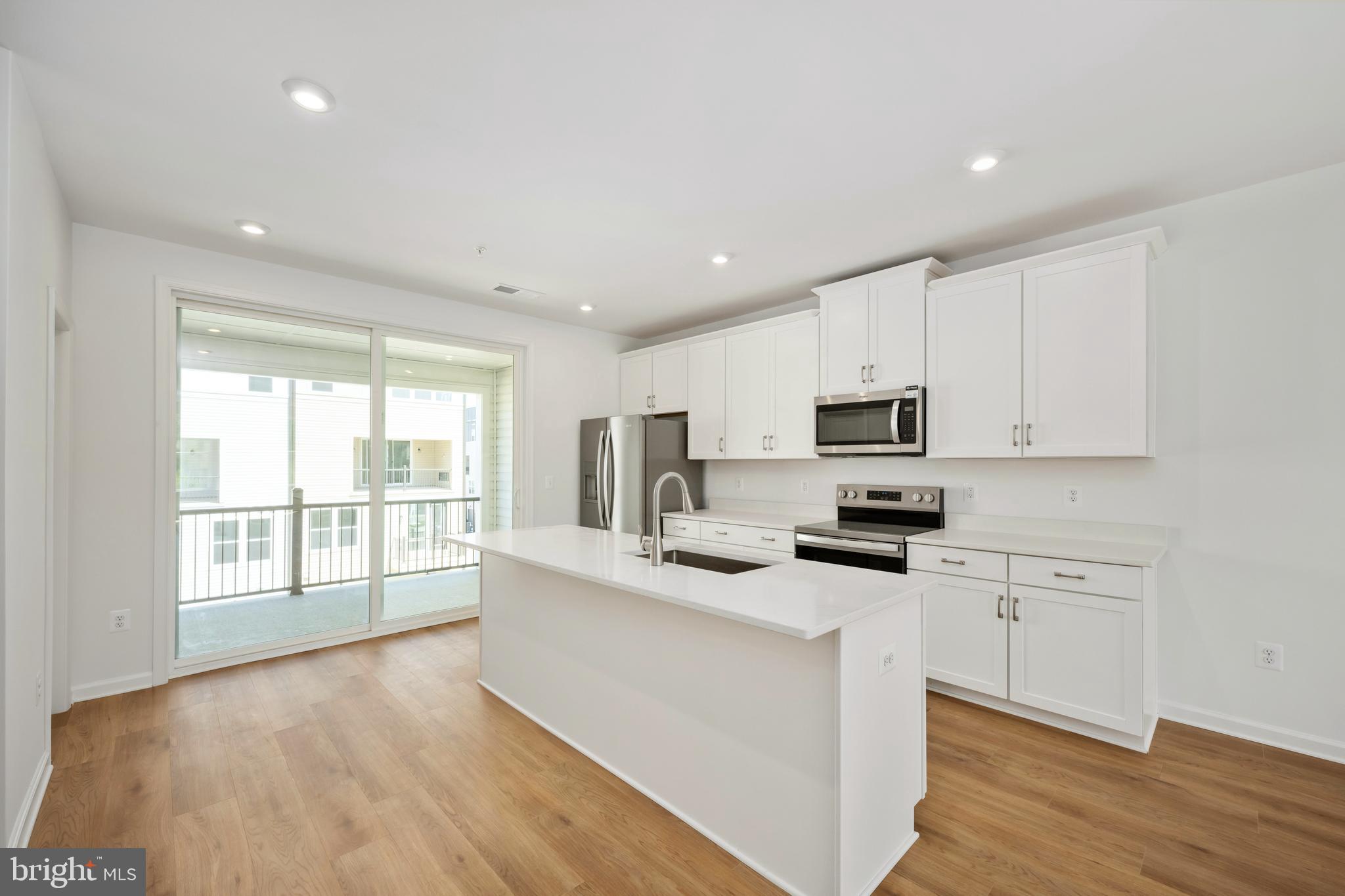 2518 Neabsco Common Place Woodbridge, VA 22191 - Photo 8 of 37 a kitchen with granite countertop a stove top oven a sink a refrigerator and white cabinets with wooden floor