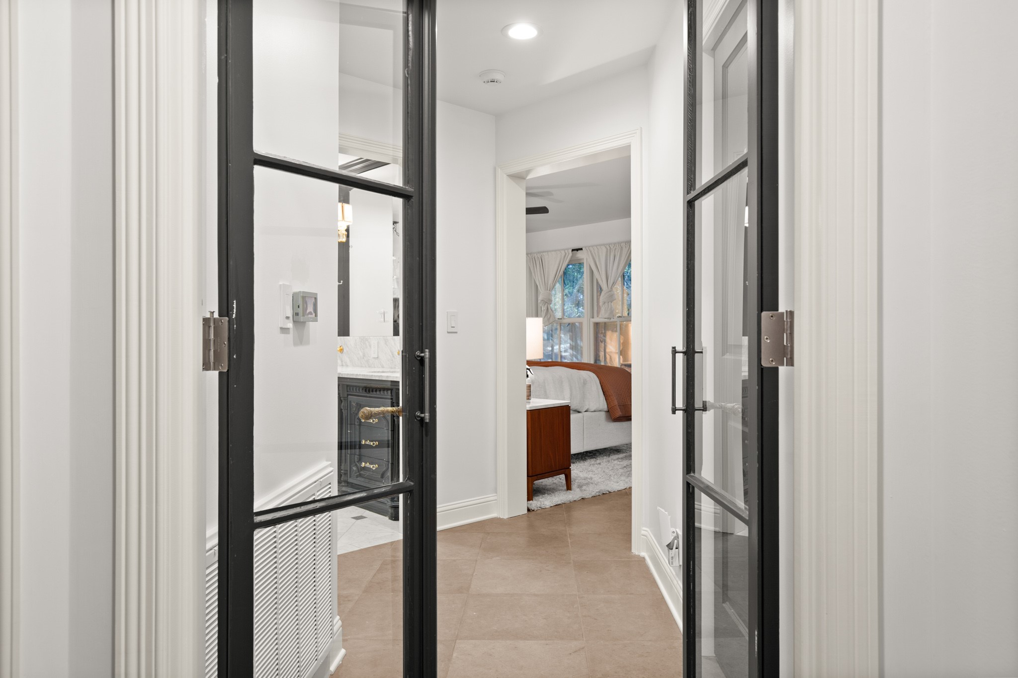 1601 Whitney Way Austin, TX 78741 - Photo 17 of 30 Black-framed glass doors open to reveal a private bathroom and serene bedroom beyond.