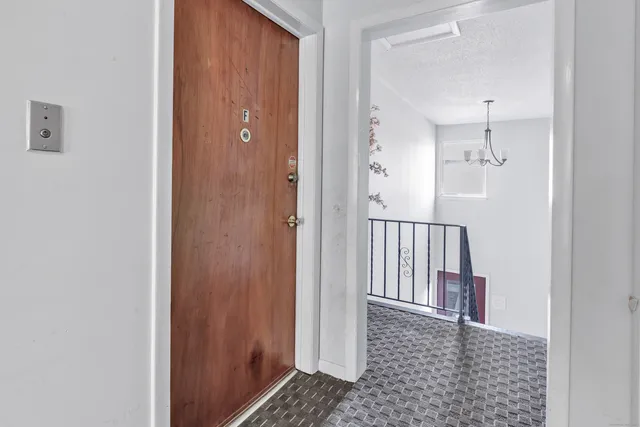a view of a hallway with wooden floor and a bathroom
