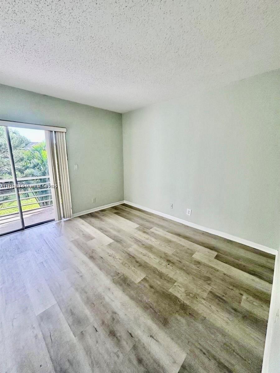 119 Salisbury East, Unit E West Palm Beach, FL 33417 - Photo 9 of 11 wooden floor in an empty room with a window