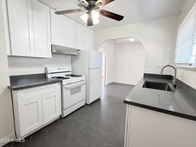 a kitchen with granite countertop white cabinets and white appliances