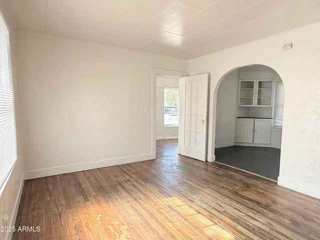 an empty room with wooden floor closet and windows
