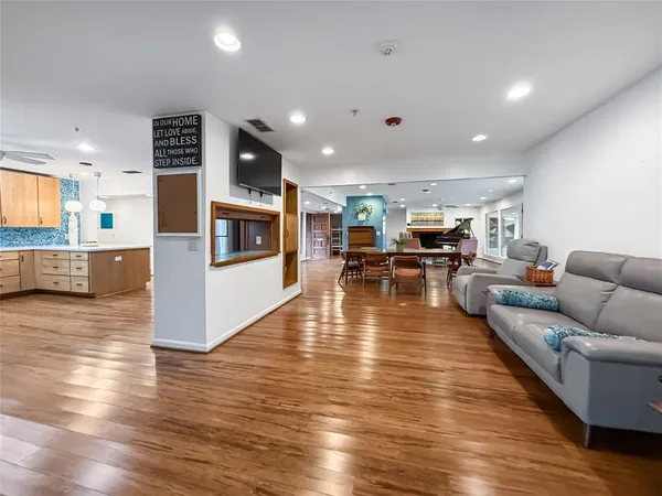 a living room with furniture wooden floor and a kitchen