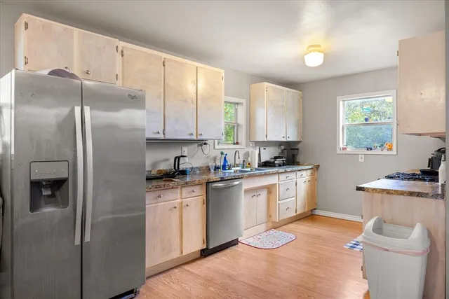 a view of an empty room with a window and wooden floor