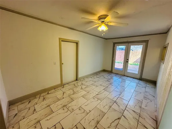 a view of an empty room with window and chandelier fan